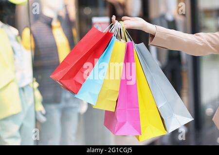 Bunte Papiertaschen auf weiblichen Händen auf dem Hintergrund des Einkaufszentrums Stockfoto