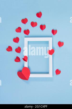 Weißer Rahmen mit roten Herzen auf blauem Hintergrund, Kopierraum, valentinstag, Liebe, Einladung Stockfoto