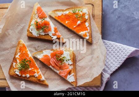 Sandwiches oder Tapas mit Brot, rotem Kaviar und rotem Fisch mit Mikrogemüse, Meeresfrüchten Luxus-Delikatessen Stockfoto