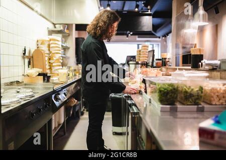 Junger männlicher Koch bereitet im Restaurant Essen zu Stockfoto