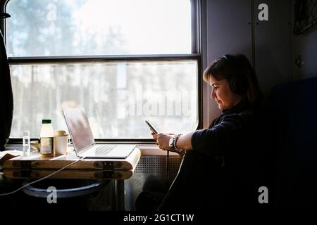 Weibliche professionelle SMS-Nachrichten über Smartphone während der Reise im Zug Stockfoto