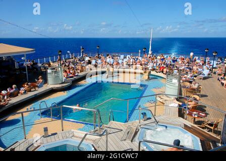 Das Schwimmbad am Heck eines Kreuzfahrtschiffes mit Menschenmassen beim Sonnenbaden, Karibik Stockfoto