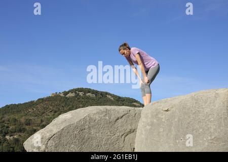 Erschöpfter Läufer, der sich nach dem Training im Berg auf einer Klippe ausruhte Stockfoto