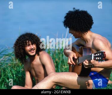 Menschen, Teenager, 70er Jahre, zwei junge Männer, Hippies mit Gitarre im Sommer sitzen auf der Wiese, ZUSÄTZLICHE-RIGHTS-CLEARANCE-INFO-NOT-AVAILABLE Stockfoto