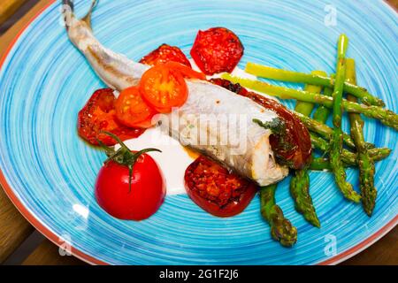 Gebackener Wittling mit sonnengetrockneten Tomaten, Sparrowgrass, Knoblauch-cremiger Sauce Stockfoto