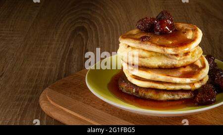 Mehrere Pfannkuchen mit Erdbeermarmelade und Beeren auf einem Holzbrett Stockfoto