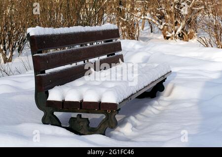 Holzbank im Winterpark nach Schneefall mit Schnee bedeckt Stockfoto
