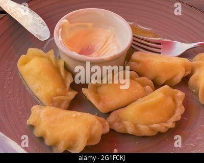 Nahansicht auf einem Teller mit traditioneller ukrainischer Wüste - Vareniky gefüllt mit Hüttenkäse, gewürzt mit saurer Rahm und geschmolzener Butter und Honig Stockfoto