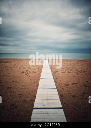 Holzweg zum Meer an einem Sandstrand. Stockfoto