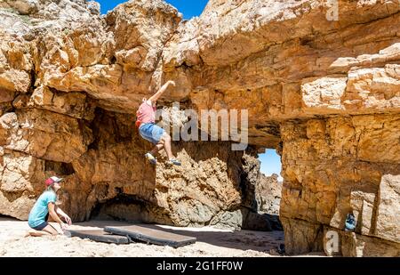 Ein Kletterer, der auf Sicherheitsmatten am Strand, Algarve, Portugal, vom Felsen fällt Stockfoto