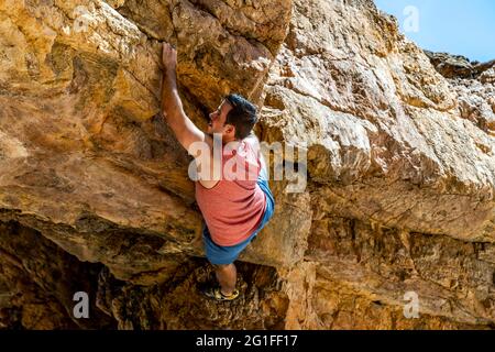 Junge Kletterer klettern sicher auf eine gelbe Klippe an der Algarve, Portugal Stockfoto