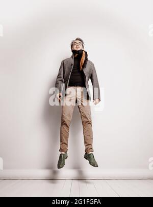 Stilvoller erwachsener Mann moderner Geschäftsmann in smarter Freizeitkleidung Hose, Karomuster und schwarzem Rollkragen springt Stockfoto