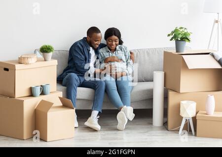 Freudig Schwanger Afroamerikanischen Paar Sitzt Auf Sofa In Ihrer Neuen Wohnung Stockfoto