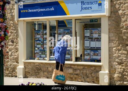 Ältere Frau, die in ein Immobilienmakler-Fenster in Dursley glos schaut. Stockfoto