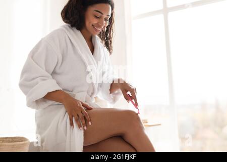 Ziemlich Afrikanische Junge Frau Herstellung Enthaarung Rasier Beine Im Badezimmer Stockfoto