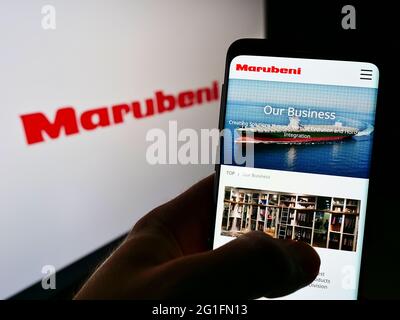 Person mit Mobiltelefon und Webseite der japanischen Handelsgesellschaft Marubeni Corp. Auf dem Bildschirm mit Logo. Konzentrieren Sie sich auf die Telefonanzeige. Stockfoto