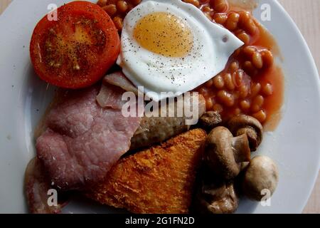 Englisches Frühstück, komplettes englisches Frühstück, Frühstückswürste, Spiegel, Spiegeleier auf der Sonnenseite, Speck, Speck, gebratene Tomaten, gebackene Bohnen, Bohnen in Stockfoto