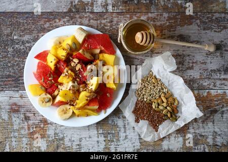Frischer saftiger Obstsalat auf einem Teller mit Mango, Grapefruit und Samen. Gesunde Ernährung. Vegane Ernährung. Stockfoto