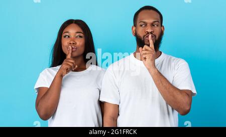 Schwarzes Paar, das Finger auf die Lippen stampft und ein Zeichen für die Stille macht Stockfoto