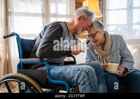 Reifer Mann mit Behinderung im Rollstuhl mit Spaß mit Frau. Familie ältere Paar Liebe Konzept Stockfoto