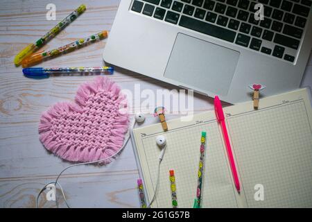 Flach liegend, Draufsicht auf Laptop, Stifte, gewebtes Hot Pad und das Notebook auf dem Holzhintergrund. Produktivitätskonzept Stockfoto