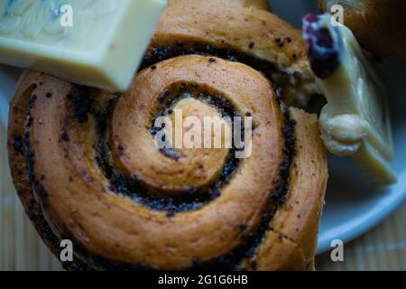 Mohnsamen-Brötchen mit Schokoladenscheiben. Dessert auf dem Teller. Leckeres Essen Stockfoto