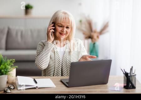 Verwirrt reife Frau sprechen auf Handy mit Laptop Stockfoto