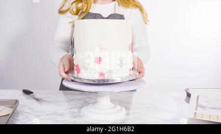 Einfügen von großen Lutscher mit Schneeflocken in den hohen Weiße, runde Kuchen als Dekoration. Stockfoto