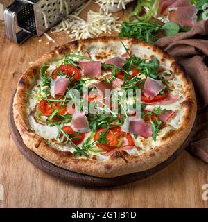 Pizza mit Prosciutto-parmaschinken, Rucola-Salat auf Holzboden. Fastfood-Mittagessen für Picknick-Gesellschaft, Foto für das Menü. Italienische Küche. Stockfoto