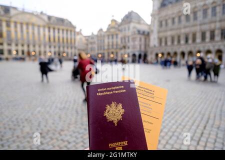 Belgien, Brüssel, 19. Februar 2021: Französischer Reisender mit seinem Pass und einem internationalen Impfpass oder Prophylaxe-Zertifikat in einer Straße von Stockfoto