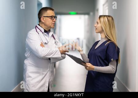 Ärzteteam arbeitet gemeinsam an der Patientenakte im Krankenhaus. Medizinisches Personal, das Bericht analysiert und in der Klinik arbeitet. Ärztin mit Diskussion in Stockfoto