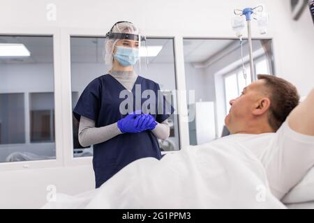 Ärztin mit PSA-Anzug und OP-Maske und Untersuchung infizierter Patienten im Quarantäneraum Covid-19 Stockfoto