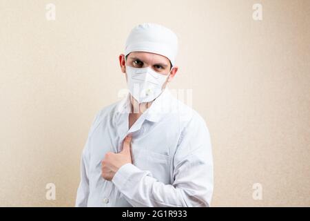 Doktor in Maske und Mütze, zeigt Daumen nach oben. Stockfoto