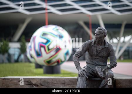 07. Juni 2021, Bayern, Herzogenaurach: Auf dem Gelände des Sportartikelherstellers adidas wurde vor dem Bürogebäude der Arena eine Statue des Gründers Adolf 'Adi' Dassler errichtet. Im Hintergrund ist ein überdimensionaler offizieller Spielball 'Uniforia' der EURO 2020 zu sehen. Die deutsche Fußballnationalmannschaft sowie die Support-Mitarbeiter bleiben während der Europameisterschaft auf dem Heimgelände des DFB-Partners adidas. Foto: Daniel Karmann/dpa Stockfoto