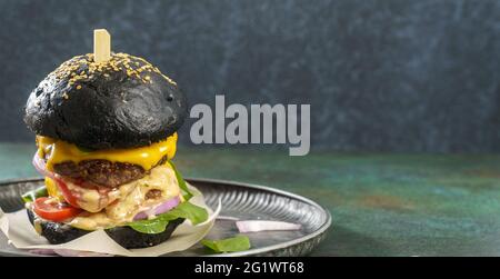 Großer schwarzer Burger mit doppeltem Rinderschnitzel, geschmolzenem Käse und Spinat mit Kopierfläche Stockfoto