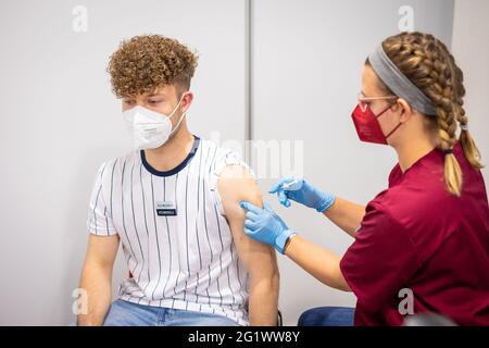 Hannover, Deutschland. Juni 2021. Maximilian Sendmeyer, Mitarbeiter der Versicherungsgesellschaft, erhält von einem Mitarbeiter des Gesundheitswesens seine erste Corona-Impfung mit dem BioNTech/Pfizer-Impfstoff. Eine Impfinitiative der in Hannover ansässigen Versicherer startete mit Corona-Impfungen. Eingeladen waren Mitarbeiter aus neun Versicherungsgruppen. Quelle: Moritz Frankenberg/dpa/Alamy Live News Stockfoto