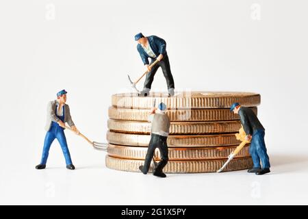 Gruppe von Bergarbeiterfiguren mit Ausrüstung, die auf einem Stapel Bitcoins arbeitet. Kryptowährung, Blockchain oder Handelskonzept. Stockfoto