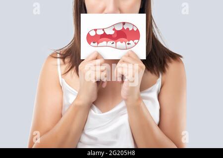 Die Frau zeigt das Bild von Kariesproblemen, Illustration Gesundheit Zahnfleisch und Zähne auf einem weißen Papier. Verfallener Zahn. Stockfoto