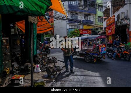 Die Menschen gehen in Talat Noi, Bangkok, Thailand, an einer belebten Straße ihren täglichen Geschäftsbetrieb durch Stockfoto