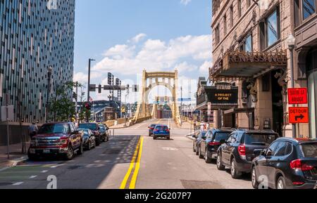 Geparkte Autos und Gebäude entlang der 6. Straße, die zur Roberto Clemente Brücke in der Innenstadt von Pittsburgh, Pennsylvania, USA führt Stockfoto