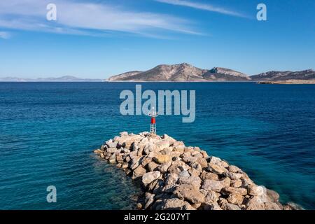 Wellenbrecher- und Beacon-Drohnenansicht. Koufonisi Insel Hafen Marina felsige Schutzmauer, kleine Kykladen Griechenland. Geriffeltes Meer und klarer blauer Himmel Stockfoto