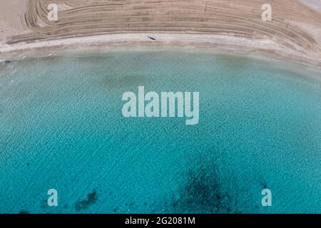 Sandstrand, klares blau türkisfarbenes Meerwasser Luftdrohne Draufsicht. Mann, der alleine auf dem Strand von Platia ammos auf der Insel Ano Koufonisi spazierengeht, kleine Kykladen. Stockfoto