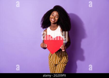 Foto von ziemlich positive dunkle Haut Dame Hände halten Papier Herz Form Postkarte isoliert auf violettem Hintergrund Stockfoto