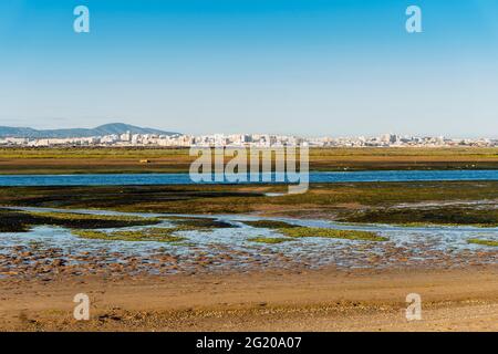 Stadt Faro von der Faro Beach Peninsula mit Feuchtgebieten der Ria Formosa dazwischen, Algarve, Portugal Stockfoto