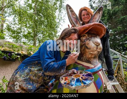 Der Künstler Chris Rutterford malt in seinem Freilichtstudio für Charity Art Trail eine humorvolle riesige Hasenskulptur, zusammen mit seinem Partner Lubi Lyken, Schottland, Großbritannien Stockfoto