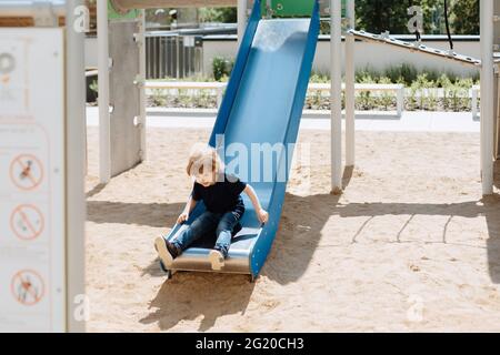 Junge 3 Jahre alt reitet Rutsche Spielplatz. Konzept der aktiven Zeit auf der Straße während der Ferien zu verbringen Stockfoto