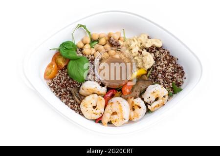 Salat mit Garnelen, warmem gegrilltem Gemüse, Quinoa, Kichererbsen, Tomaten und Hummus. Essen zum Mitnehmen. Ausgewogenes Mittagessen. Stockfoto