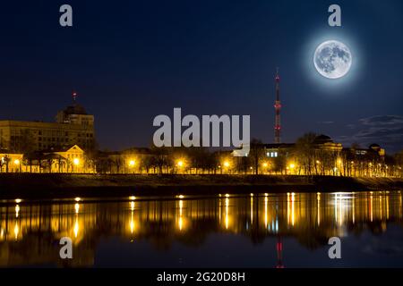 Vollmond über der Stadt. Nachtlandschaft. Laternen werden im Wasser reflektiert. Supermoon. Stockfoto