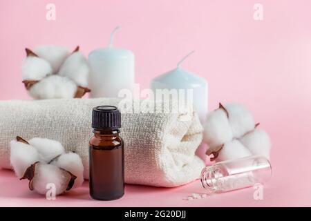 Kosmetische Produkte für Spa und Aromatherapie. Kerzen, Meersalz, Handtuch und Blumen auf rosa Hintergrund. Hautpflege- und Schönheitskonzept. Platz für Ihre te Stockfoto