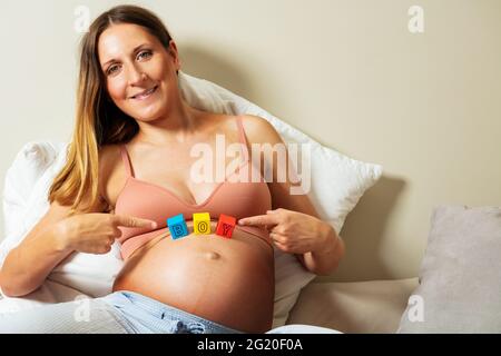 Lächelnd schwanger erwarten Frau zeigen Junge Wort Stockfoto